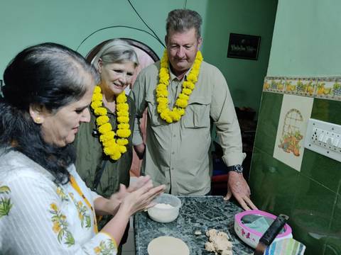 People wearing flower garlands making flatbreads.