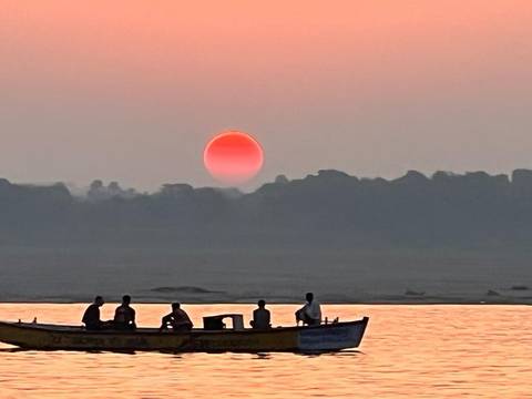Silhouette of people in a boat with a vivid red sunset.