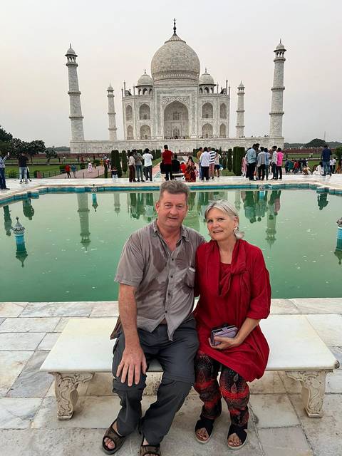 Two people sitting near a reflective pool at the Taj Mahal.