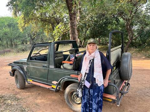A woman standing next to an off-road vehicle in a forested area.