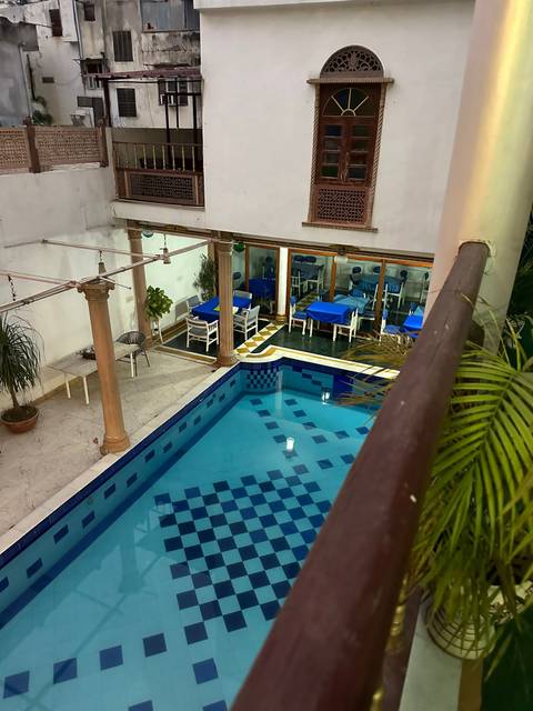 Indoor swimming pool with tables and chairs arranged nearby.