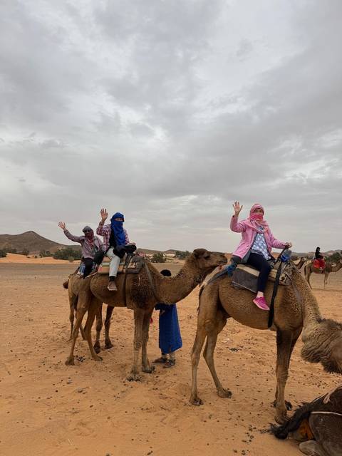 People riding camels in a desert landscape.