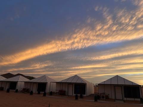 Tent camp under dramatic sky at sunset.