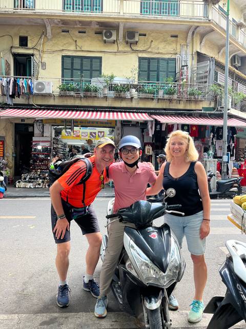 Three people posing in a street with shops.