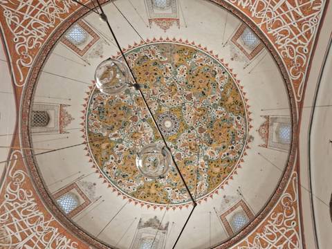 Intricately decorated dome ceiling with hanging lamps.