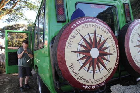 People preparing to enter a green safari vehicle featuring branded tire covers.