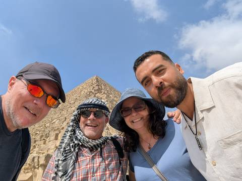 Group of people taking a selfie with a pyramid in the background.