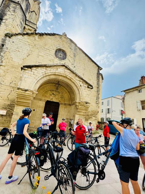 People with bicycles in front of a historic building in a quaint European town.