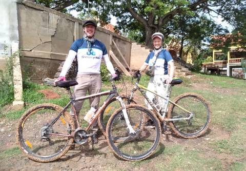 Two cyclists with muddy bikes posing together.