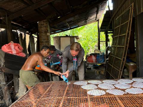 Locals and tourist cooking together in a rustic kitchen.