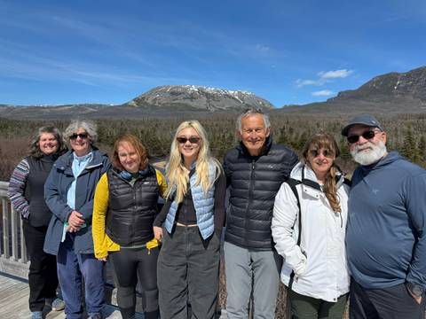 Group of people in winter clothing with a mountain in the background.