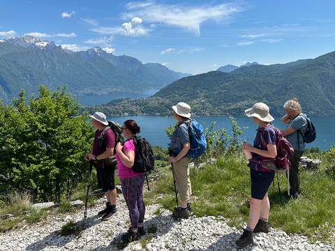 Group of hikers enjoying a view of a vast lake and mountain range.
