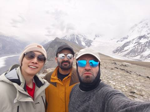 Three people posing in a mountainous area with snow.