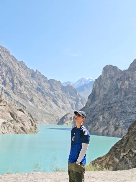 Person wearing sunglasses looking at a distant mountain range with a lake.