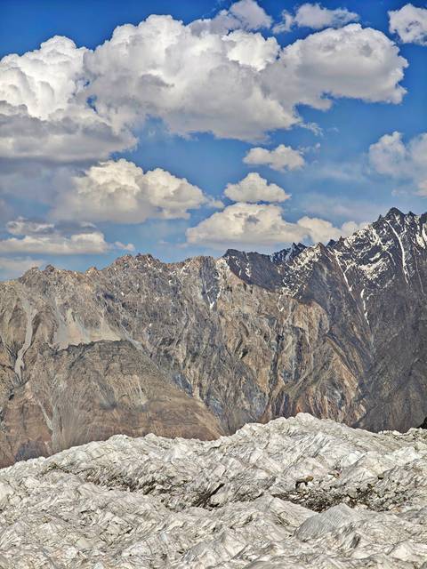 Mountain range with rocky terrain under a cloudy sky.
