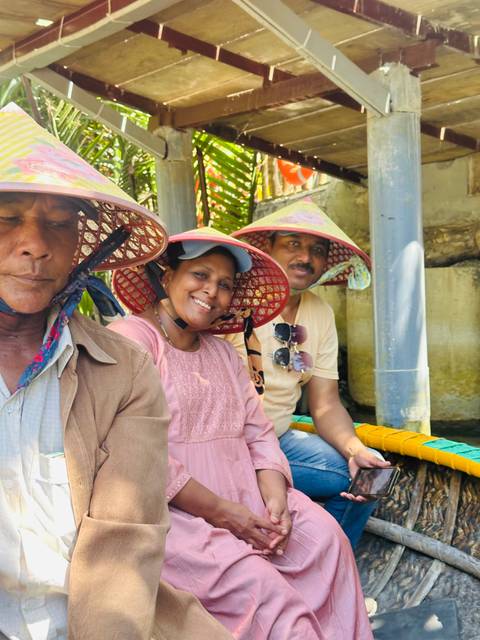 Family on a rowing boat through lush trees in the Mekong Delta.