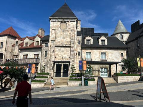 Stone building in a theme park with cloudy skies.