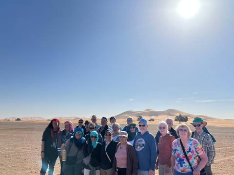 Group of tourists in a desert landscape with sand dunes.