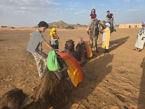 People riding camels in desert landscape.