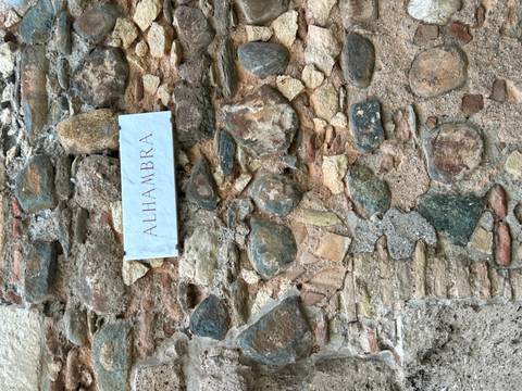 Sign indicating 'Alhambra' on a stone wall.
