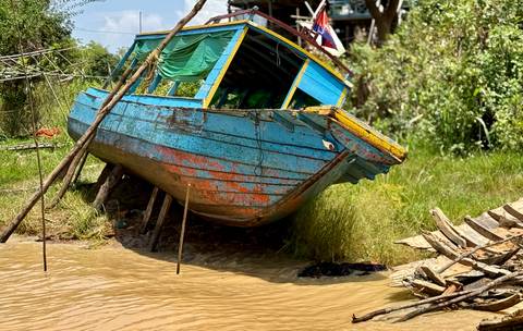 Colorful boat grounded near water's edge.