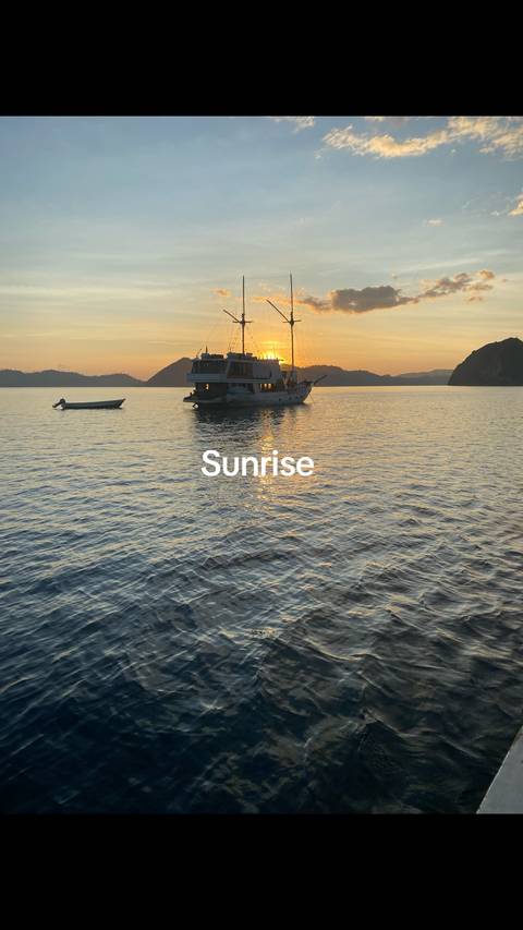 Sunrise over water with boats in the distance and a visible watermark.