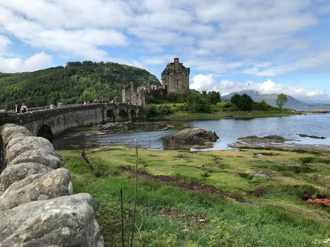 Eilean Donan Castle surrounded by greenery and a stone bridge.