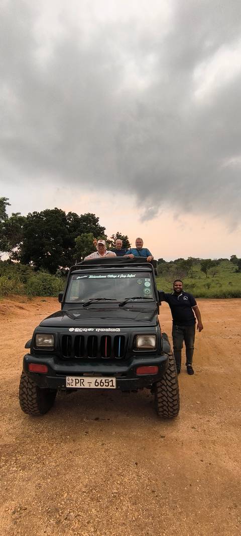 A group of people standing on a jeep in a safari setting.