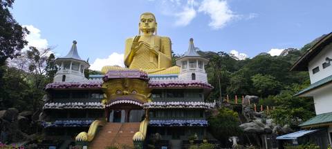 A golden Buddha statue at a temple with stairs leading up.