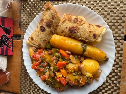 Plate of traditional food with chapati, potatoes, and vegetables.