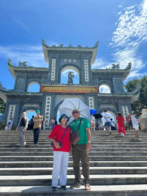 Tourists standing at the entrance of a temple or pagoda with an archway.