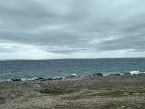 Rocky coastline with waves under a cloudy sky.