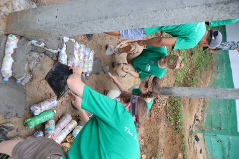 Group of people working with recycled bottles and cement.