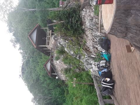 Buildings on a rocky hillside with bags and equipment in the foreground.