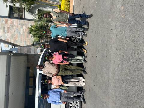 Group of people standing in front of a vehicle.