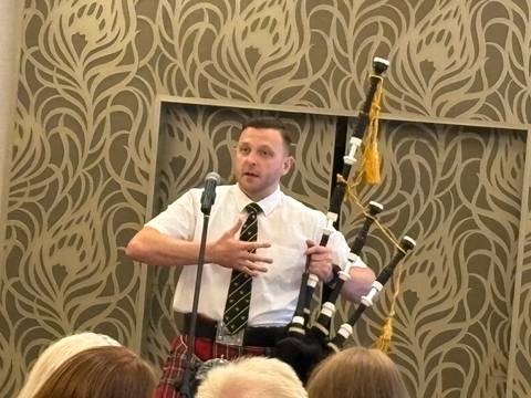 A man with bagpipes speaking into a microphone.