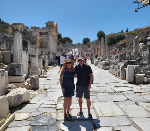 Tourists walking down an ancient street lined with ruins.