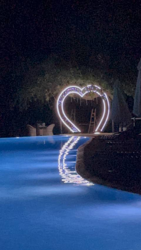 Heart-shaped lights near a pool at night.