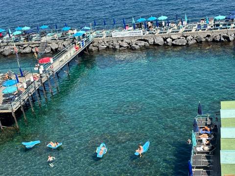 Aerial view of a beach with people and kayaks on a clear day.