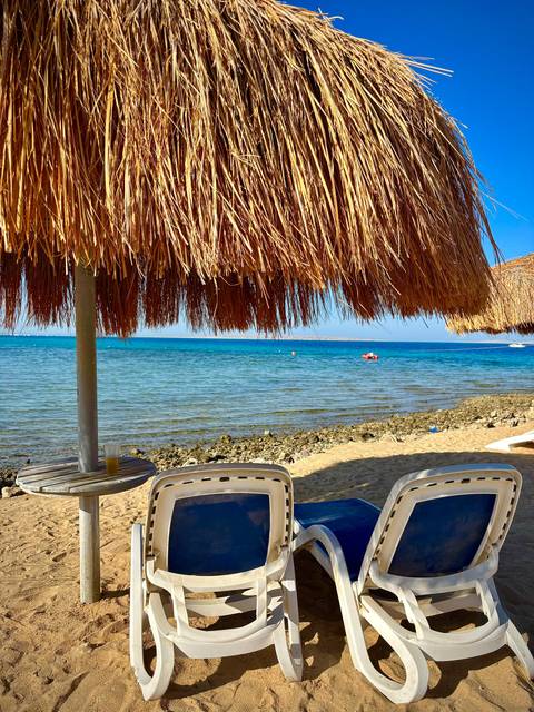 Beach with clear water and thatched umbrellas.
