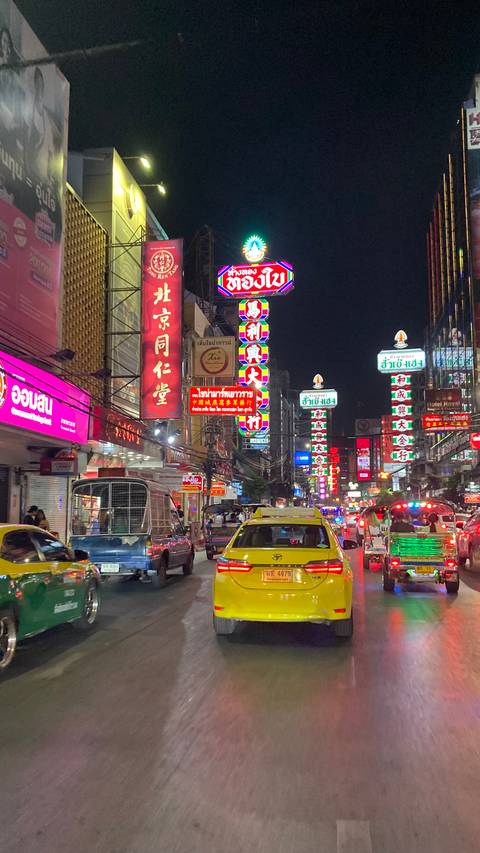 Night street scene with signs and taxis in a bustling area.