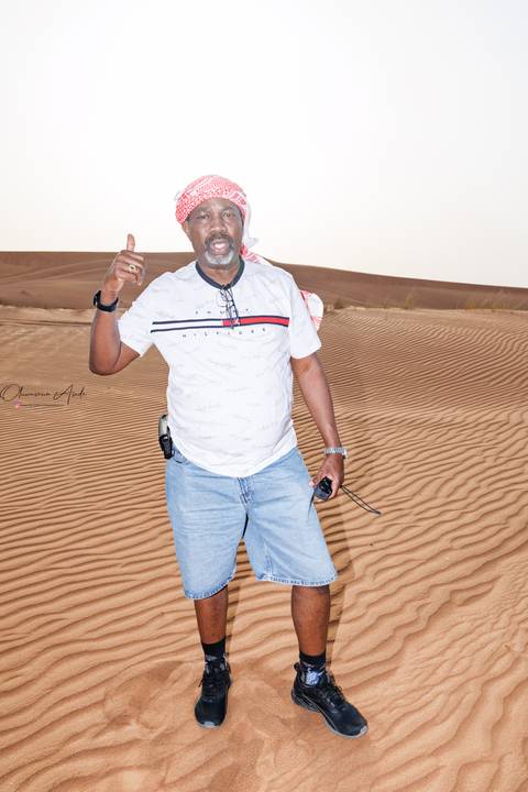 Man standing in the desert wearing a headscarf.
