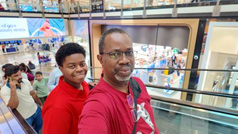 Two people on an escalator in a shopping mall.