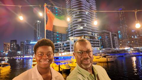 Two people at night with marina and city lights in the background.