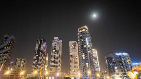 Night view of skyscrapers with a glowing moon.