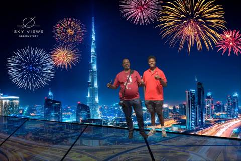 Two people posing with fireworks and skyscrapers in the background.
