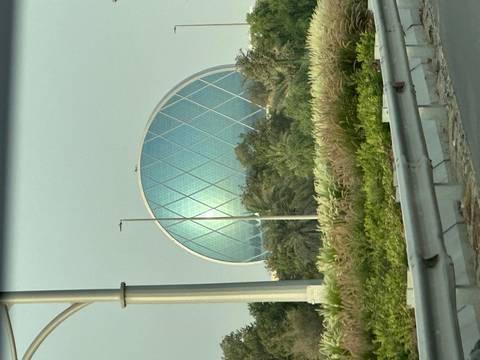 Unique circular glass building among greenery.