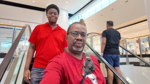 Two people on an escalator in a mall.