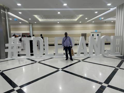 Man posing with a large sign that reads 'TOLERANCE'.