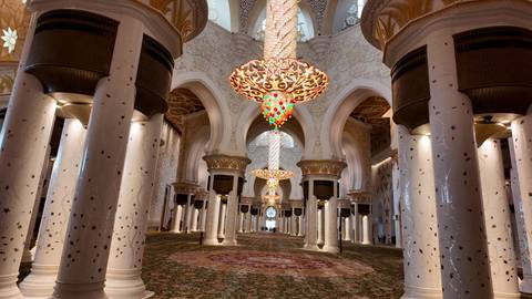 Interior of a mosque with elaborate chandeliers and arches.